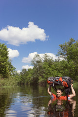 Fototapeta na wymiar Man crossing the river with a backpack.
