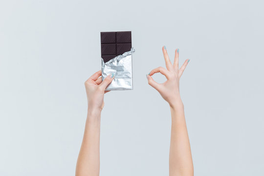 Female hands holding chocolate and showing ok sign