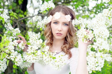 Fototapeta premium Spring / pretty woman with flower hair band in front of a blossoming apple tree