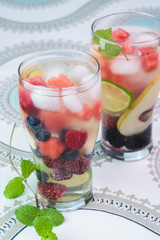 Glasses of fruit and berries, mint infused water with ice.