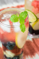 Glasses of fruit and berries, mint infused water with ice.