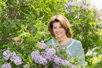 Adult woman in park near the blossoming lilac