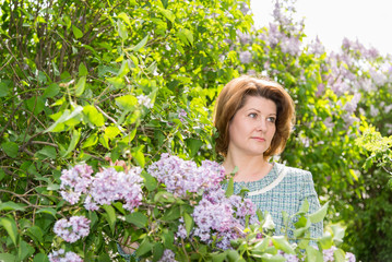 Adult woman in park near the blossoming lilac