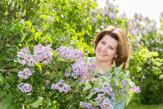 Adult woman in park near the blossoming lilac