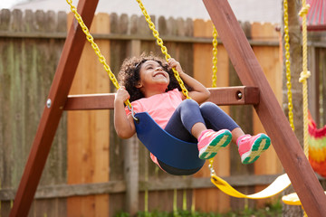 Kid toddler girl swinging on a playground swing - obrazy, fototapety, plakaty