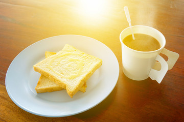 Hot coffee and bread toast topped with milk for breakfast and the morning sunshine touched