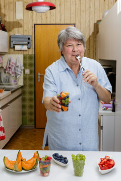 Lachend genie&szlig;t Seniorin ihren Obstbecher