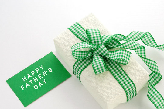 Creamy gift on a white background with a plaid green ribbon. Greeting card. Father's Day.