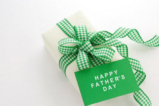 Creamy gift on a white background with a plaid green ribbon. Greeting card. Father's Day.