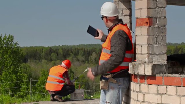 Builder using tablet PC near to the building