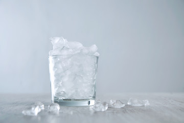 Isolated whiskey rox glass full of crashed ice cubes on wooden table white background
High key image