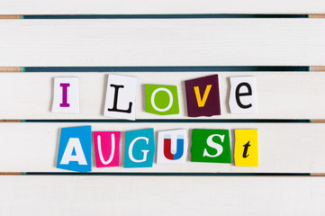 I Love August written with color magazine letter clippings on wooden board. Summer vacation concept, empty space for text