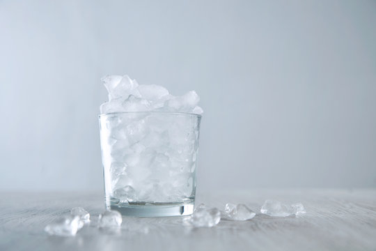 Isolated whiskey rox glass full of crashed ice cubes on wooden table white background
High key image