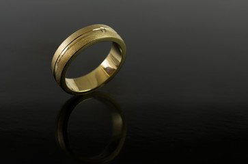 Close up of a gold ring with diamond on black background