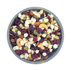 Nuts and fruit trail mix in a bowl top view isolated on a white background