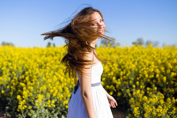 Naklejka na ściany i meble Beautiful young woman enjoying spring in a field.