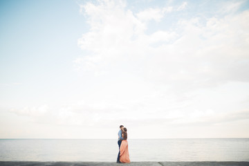Fototapeta na wymiar Beautiful loving couple, pride with long dress walking on pier