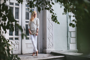 beautiful woman in white standing at the door of the house among trees