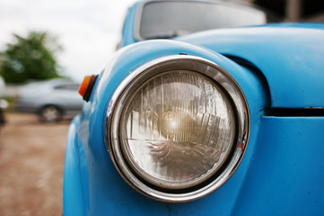 Old vintage car headlight close up at blue car.