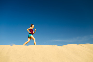 Young woman running on sand desert dunes