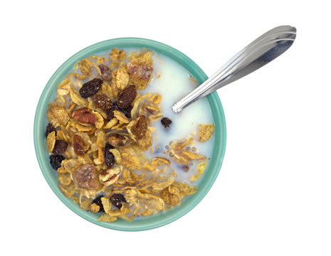 Bowl of breakfast cereal with milk and spoon top view isolated on a white background.