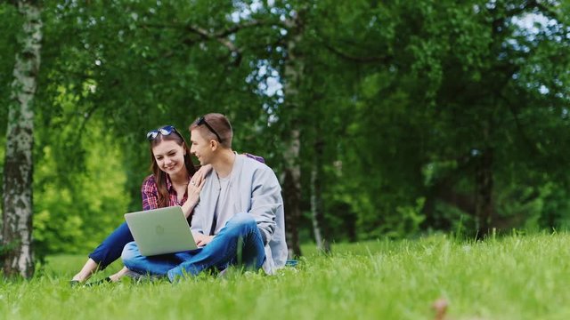 With technology on nature - a couple with a laptop in the park