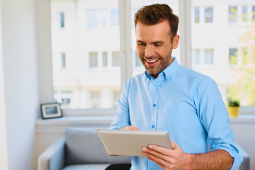 Happy man using digital tablet at home