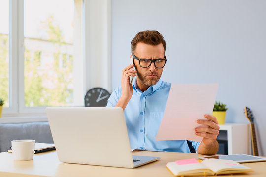 Angry Man Paying Bills And Talking On The Phone