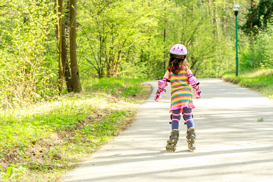 young girl in protective equipment and rollers in park, outdoor