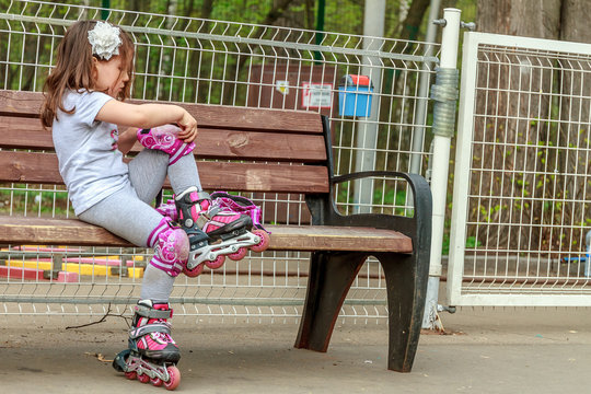 young girl in protective equipment and rollers in park, outdoor