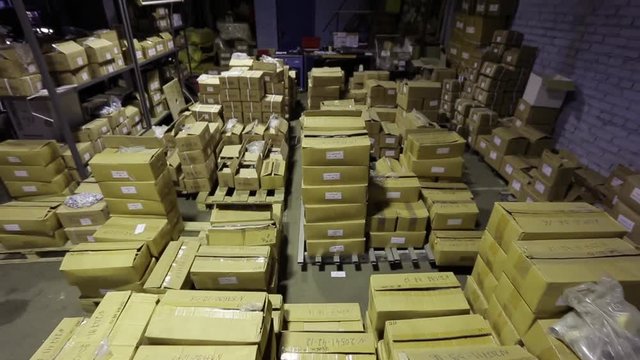 the camera shows a warehouse with boxes from different places.Steadicam stabilized shot.