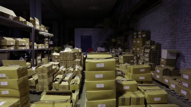 the camera shows a warehouse with boxes from different places.Steadicam stabilized shot.