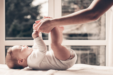 Cute baby girl plays with mothers hands