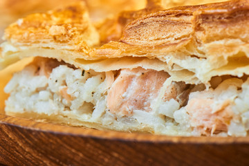 The pieces of the pie with a filling of salmon on a wooden table