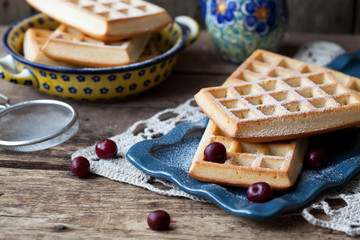 Belgium whole wheat waffles with cherry and powdered sugar on wooden table, selective focus. Dark photo.