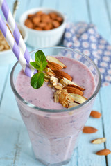 smoothie with blueberries and almonds in a glass on a blue backg