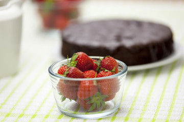 Glass bowl of strawberry's in front of a chocolate cake