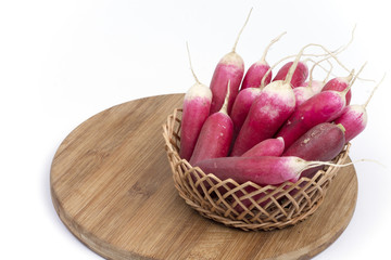 Radishes in the basket on the wooden board