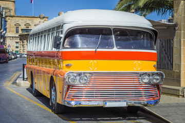 The red and orange coloured iconic Maltese public bus in the Valletta seaside road in Malta