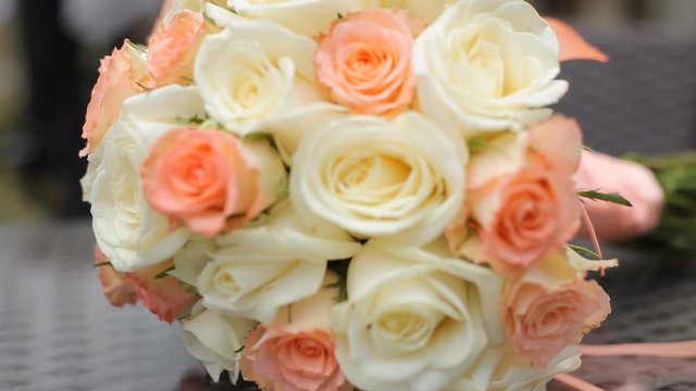 Bridal bouquet of orange and white roses on brown wooden table