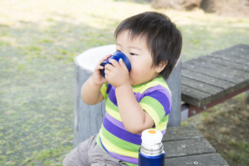 公園で水筒のお茶を飲む男の子