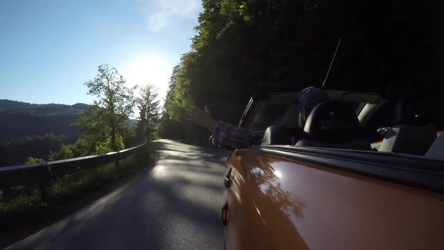 Man driving convertible car at sunset
