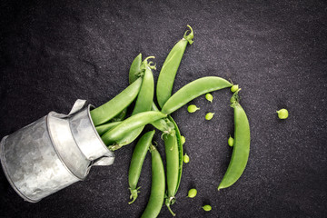 fresh green sweet peas  on black stone background