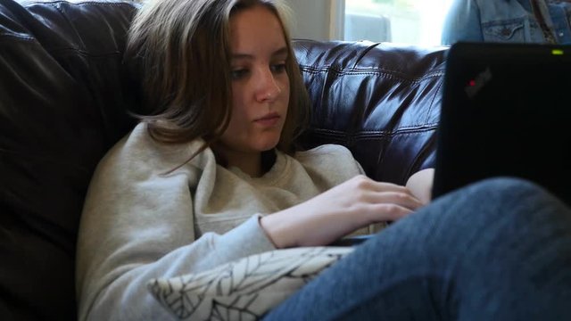 A teenage girl doing her homework on a laptop computer
