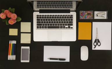 
Flat lay photo of office desk with laptop and and lots of stationery objects
