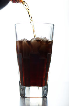 pouring brown soda into glass
