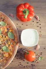 Vintage photo, Vegetarian pizza and ingredients with spices on rustic wooden background