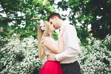Fototapeta na wymiar Stylish beautiful happy wedding couple kissing and embracing in Botanical Garden