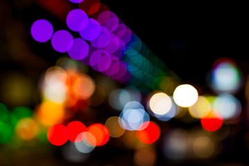 Bokeh of lights on buildings along the sidewalks .
