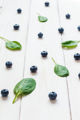blueberries and spinach leaves on wooden white background